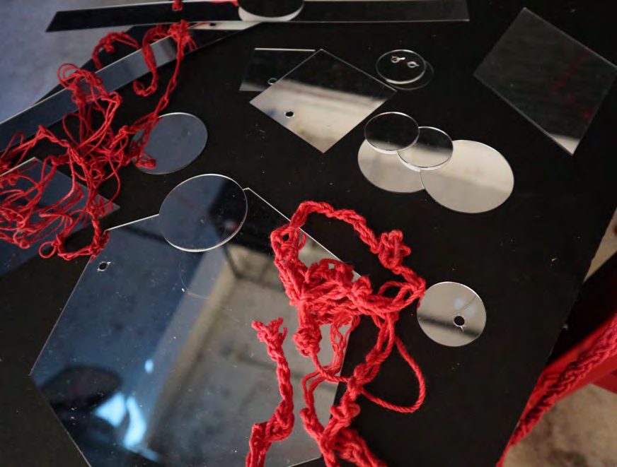 Red yarn among mirrors and metal clothes pegs on a dark surface