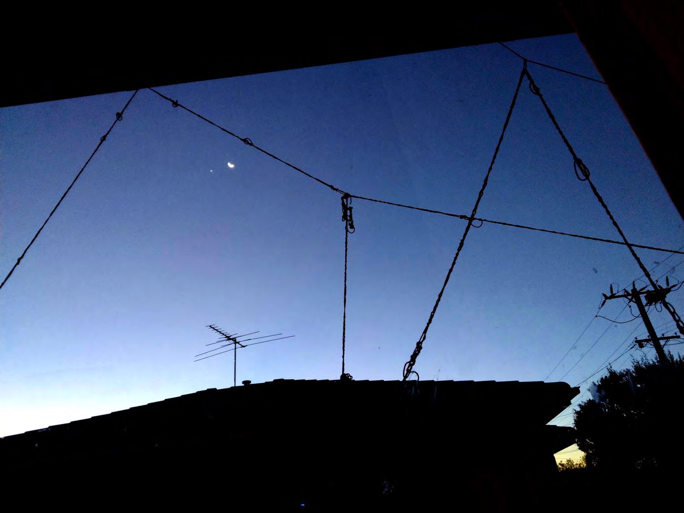 Red yarn lines strung against a darkening sky above rooftops