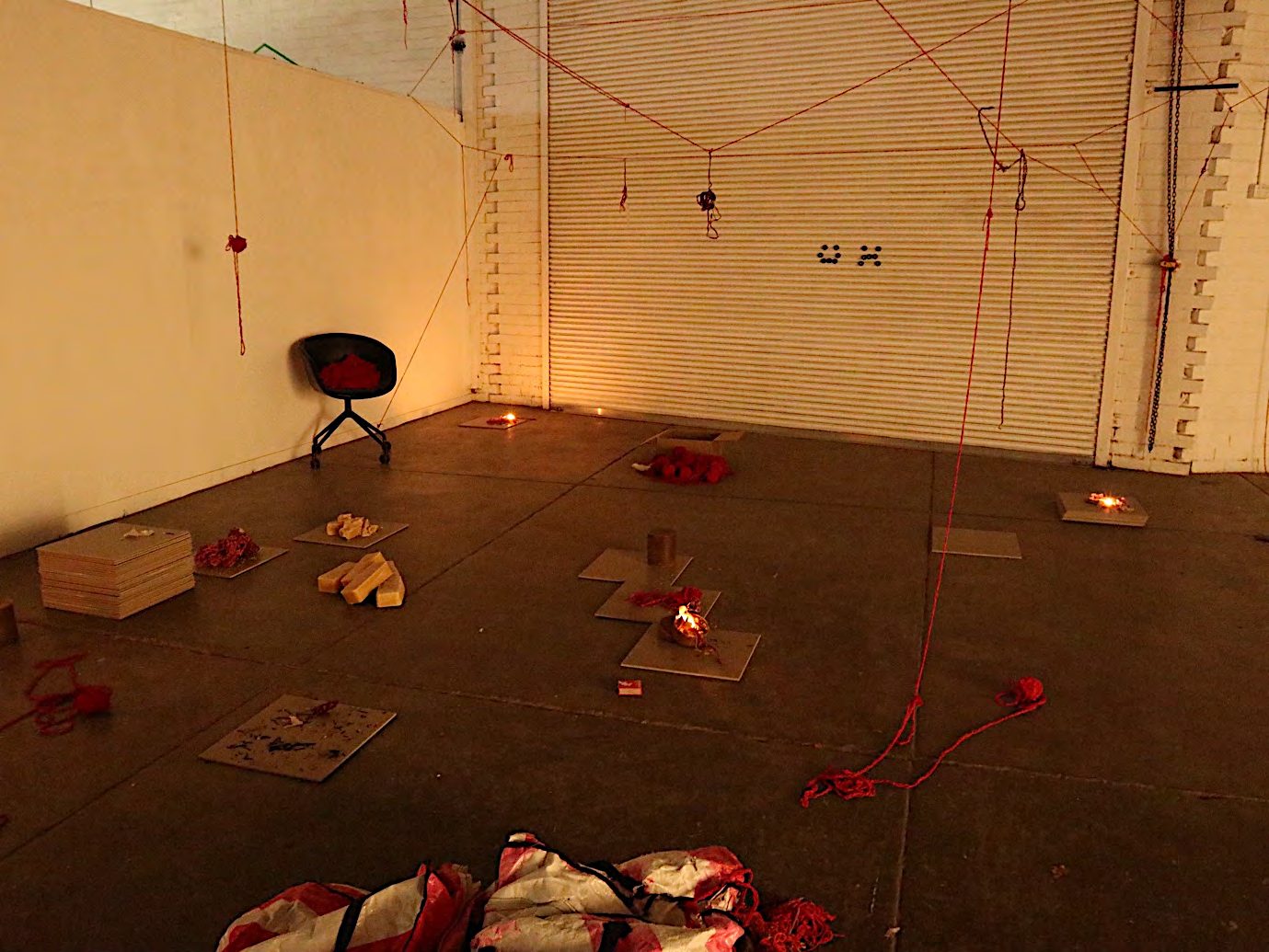 Small flames among yarn and ceramic tiles on a gallery floor