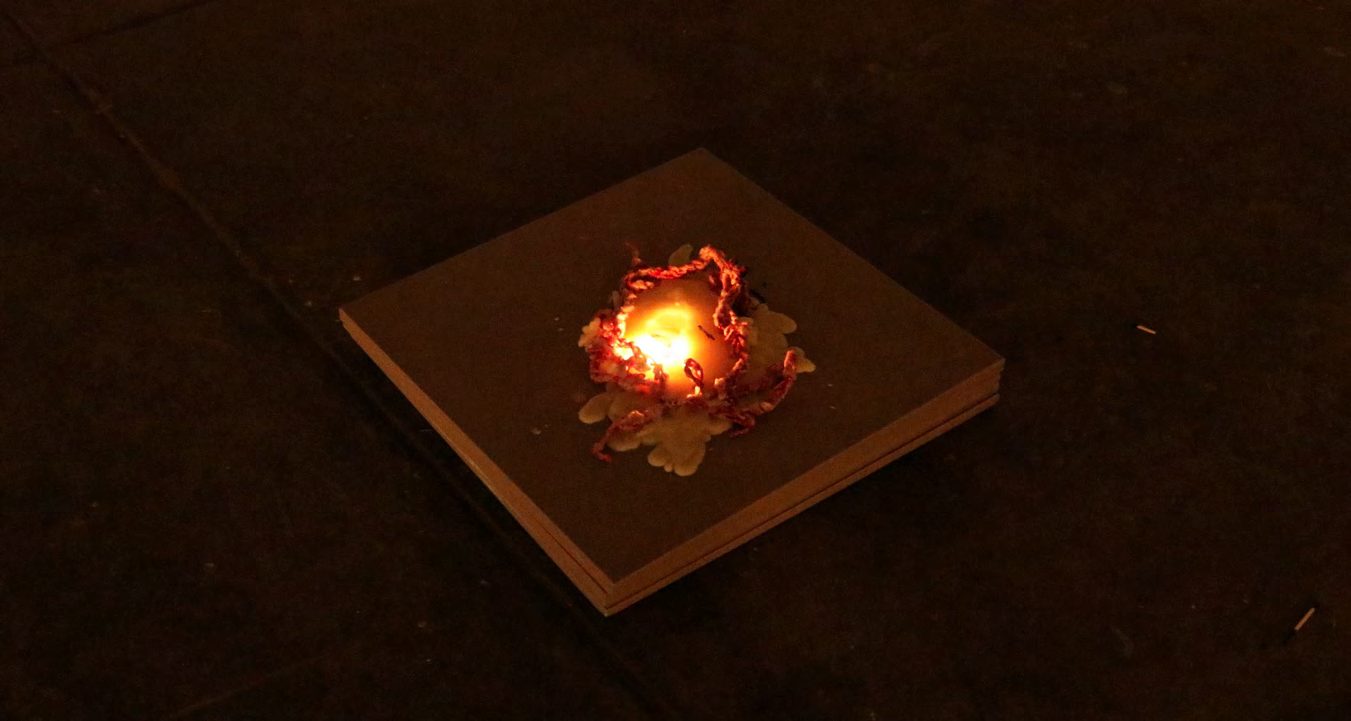 A small fire burning on a tile in darkness