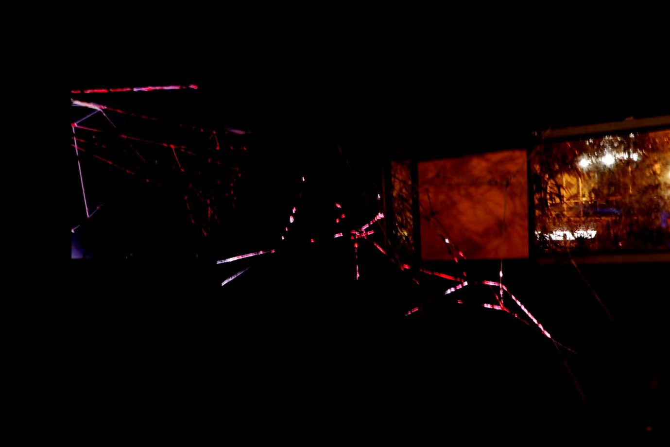 Red yarn lines lit in a dark space with projected light